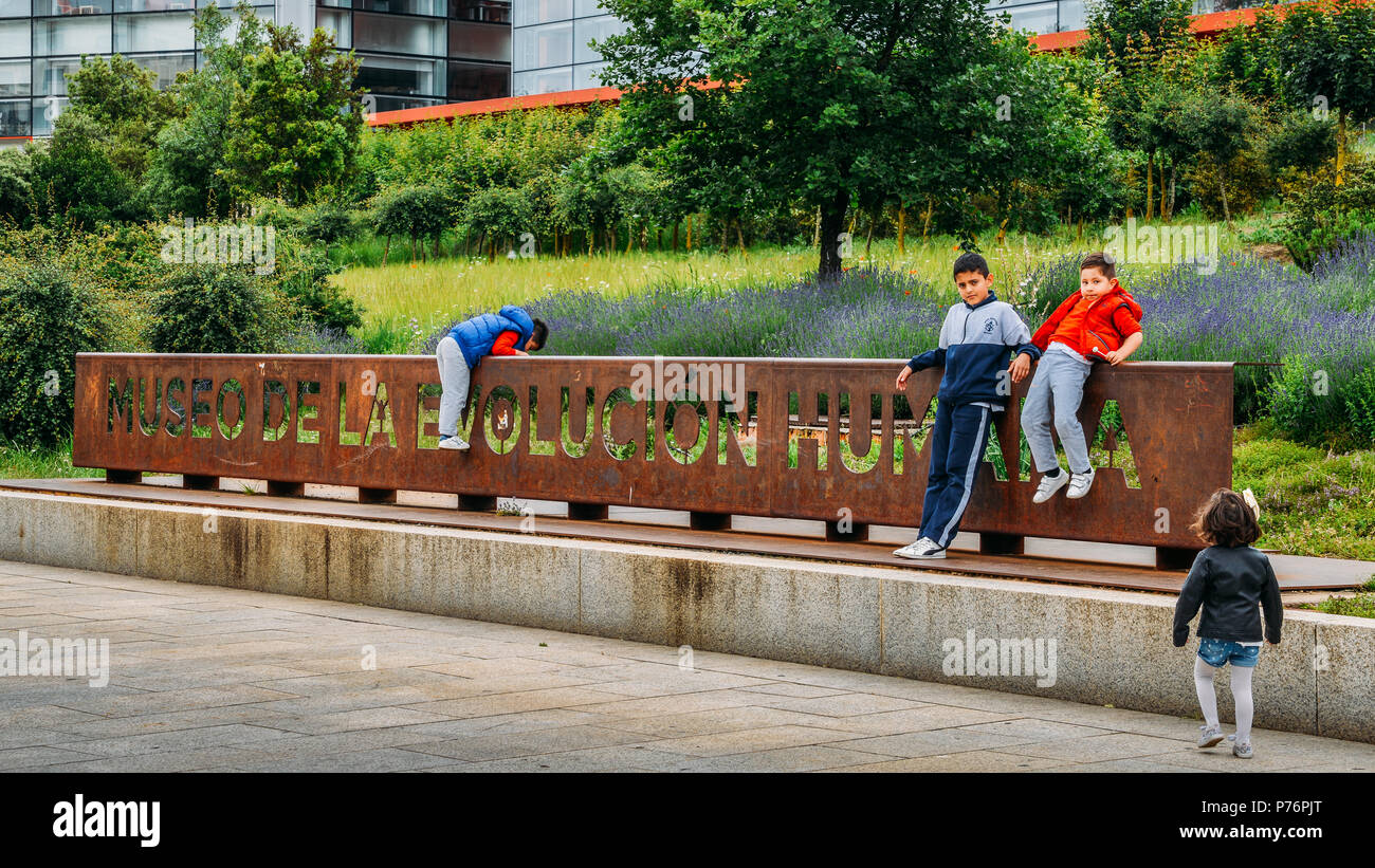 I bambini giocano su un segno davanti al Museo della evoluzione umana di Burgos, Spagna un museo sul tema della evoluzione umana Foto Stock