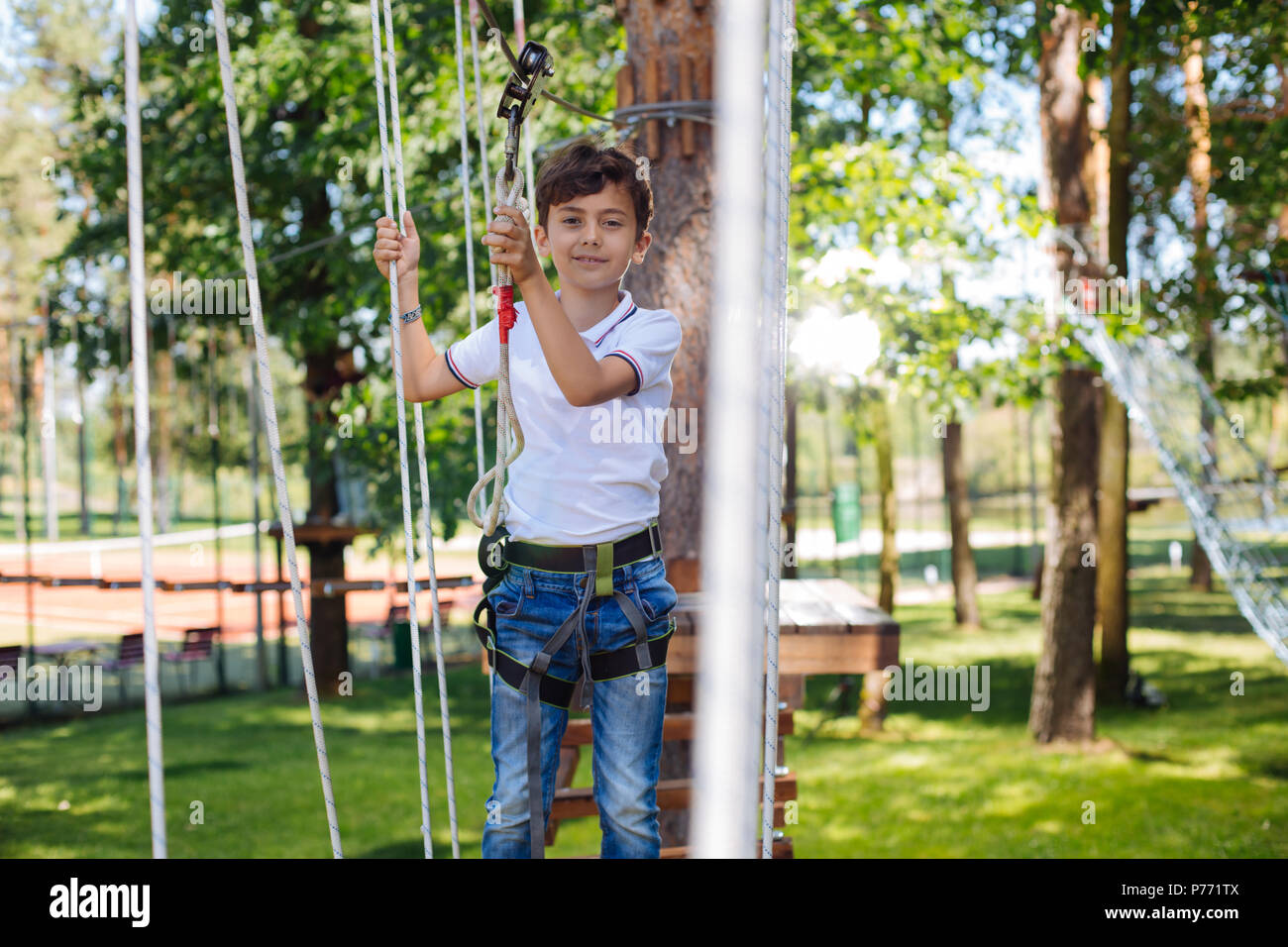 Piacevole preteen boy divertirsi al parco di corda Foto Stock