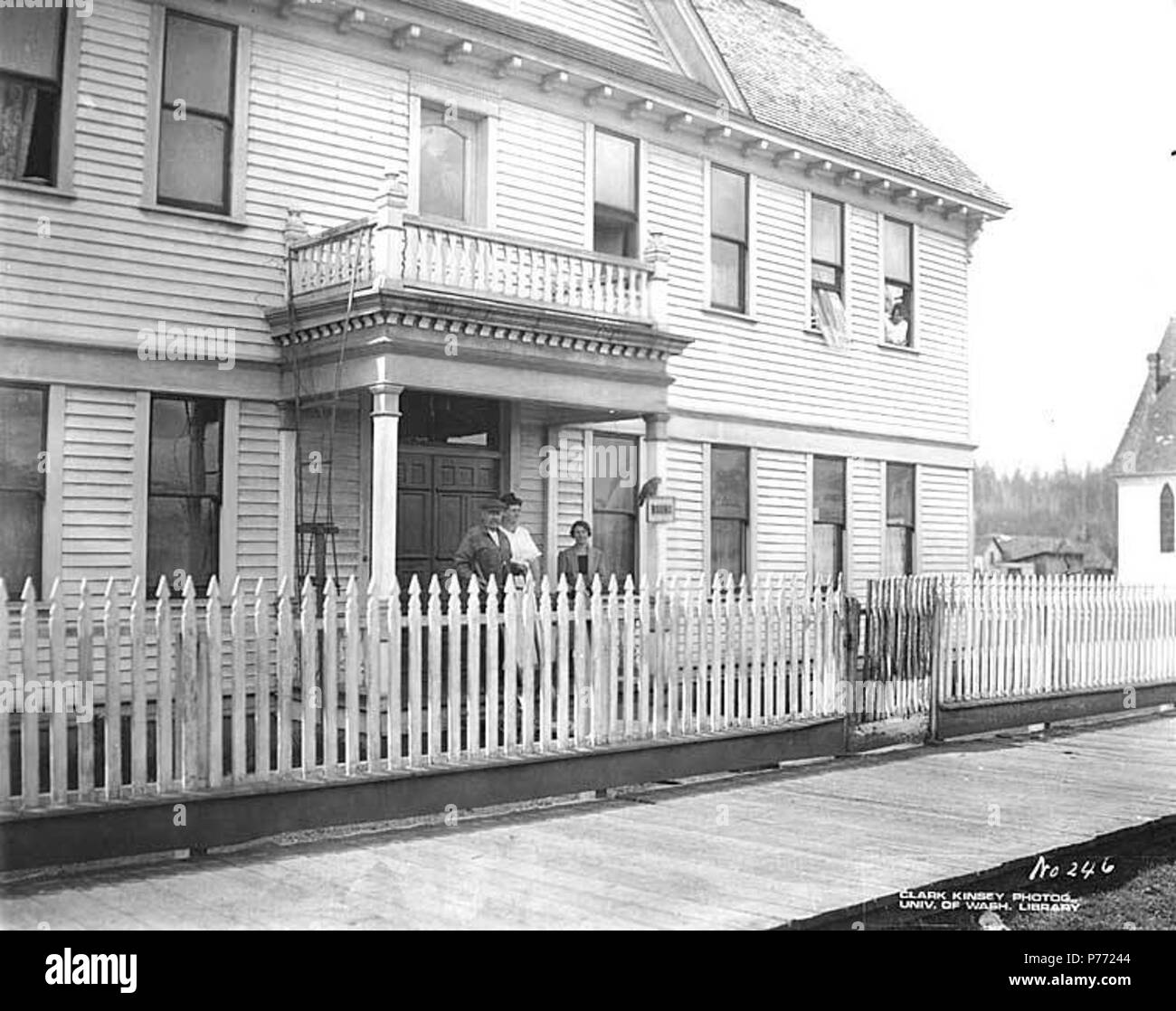 . Inglese: casa di imbarco con persone e pappagallo sul segno, probabilmente Pe Ell, ca. 1920 . Inglese: didascalia sull'immagine: No. 246 PH Coll 516.5266 Antedating la ferrovia, Pe Ell era stata risolta a volte prima del 1890 come una piccola azienda agricola comunitaria, ma la tranquilla vita agricola fu di breve durata. Nel 1892 è arrivata la Northern Pacific Railroad line per South Bend, e con essa, nel 1894, la Yeoman legname Azienda mill, prima della stringa di grandi mulini tra Chehalis e South Bend. Situato in una zona agricola e a metà strada sulla linea, Pe Ell prosperò come centro commerciale per i campi di registrazione e il vicino mulino tow Foto Stock