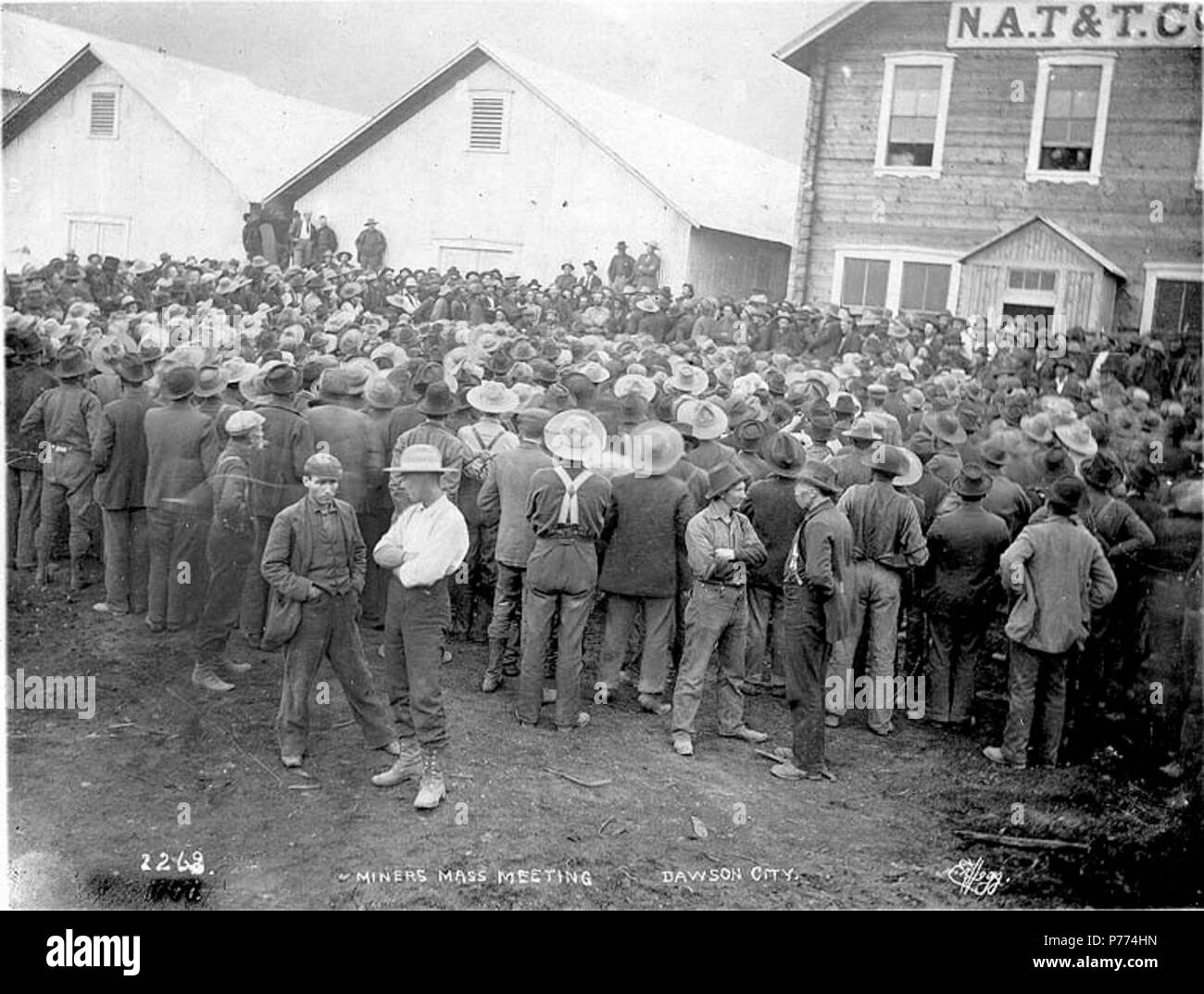 . Inglese: minatori riuniti per sale riunioni al di fuori del Nord America e di trasporto Trading Co., Dawson, Yukon Territory, ca. 1898. Inglese: didascalia sull'immagine: 'Miners incontro di massa Dawson City' Klondike Gold Rush. Soggetti (LCTGM): Gold Miner--Yukon--Dawson; Riunioni--Yukon--Dawson soggetti (LCSH): North American Transportation e Trading Company . circa 1898 9 minatori riuniti per sale riunioni al di fuori del Nord America e di trasporto Trading Co, Dawson, Yukon Territory, ca 1898 (HEGG 77) Foto Stock