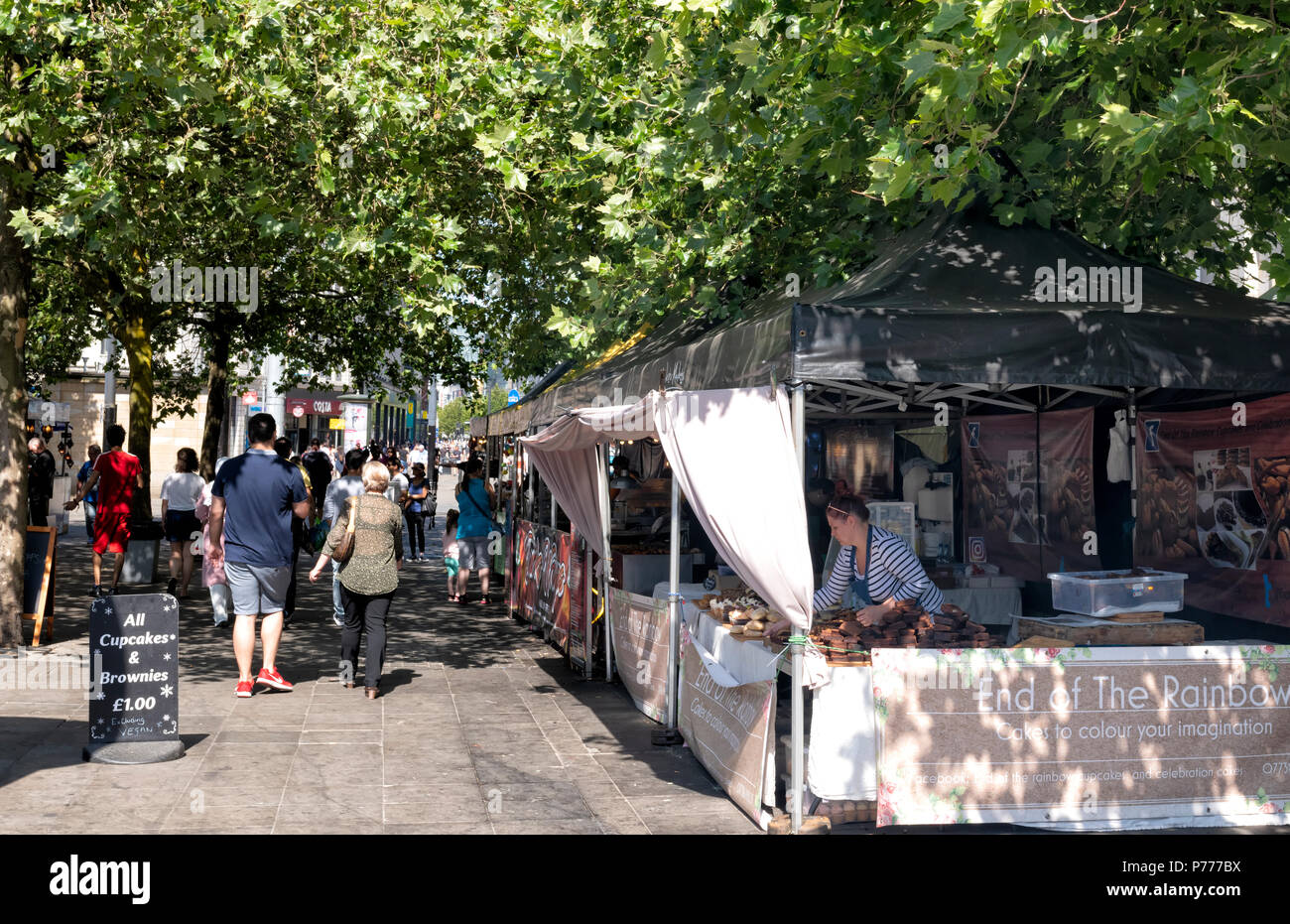 Fresatura di persone intorno a varie bancarelle prodotti alimentari in un mercato aperto, vicino a Piccadilly Gardens nel centro di Manchester, Regno Unito Foto Stock