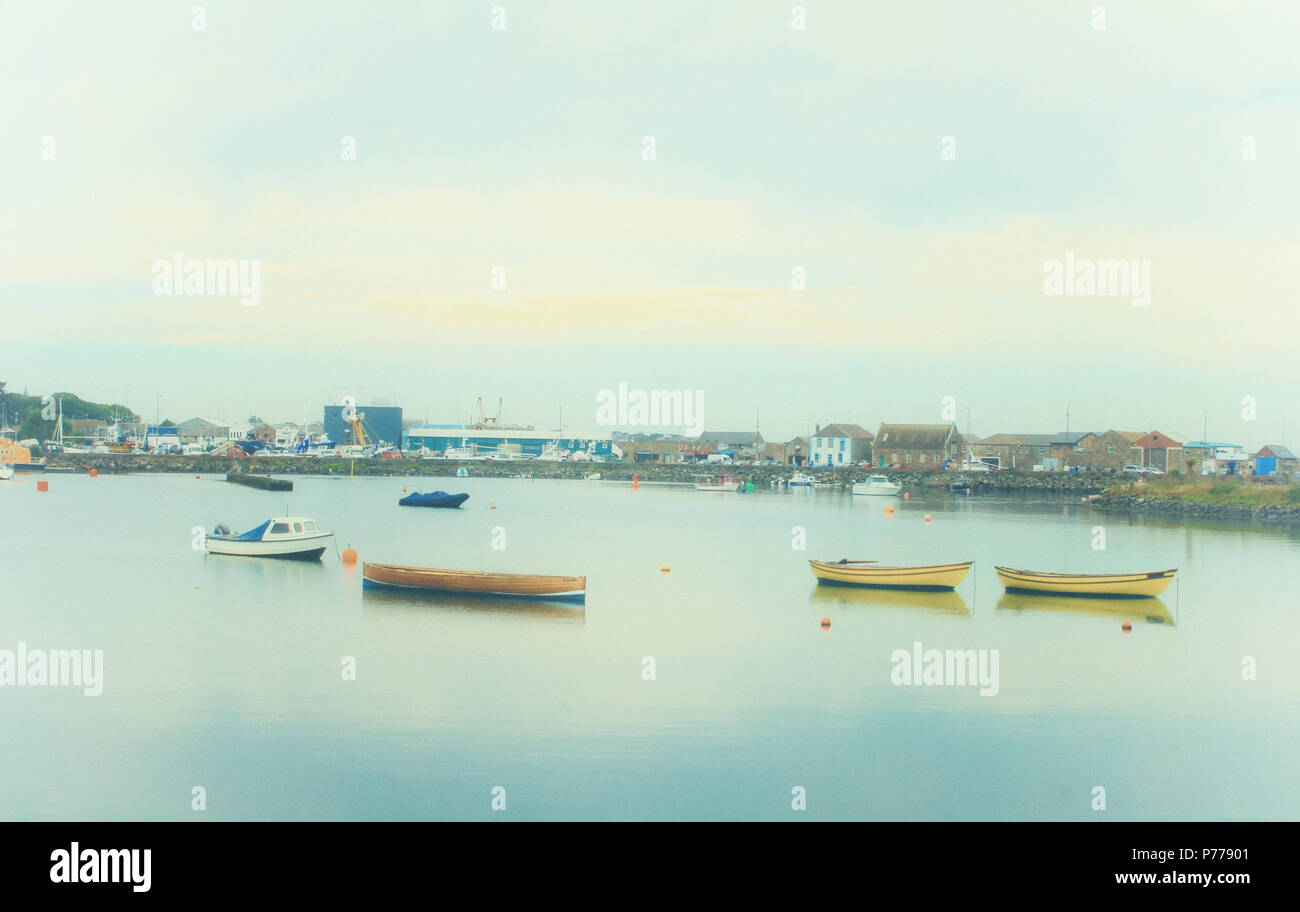 Una vista di Howth Harbour con piccole imbarcazioni in primo piano e il molo di ponente in background in una nebbiosa giornata d'estate. Foto Stock