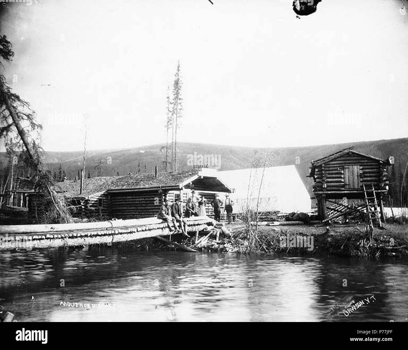 . Inglese: Insediamento presso la bocca di Hunker Creek, Yukon Territory, ca. 1898. Inglese: mostra gli uomini seduti sul ponte di fronte delle cabine di registro, della lettura del segno 'Storage' in background . Didascalia sulla immagine: 'bocca Hunker dell' soggetti (LCTGM): Fiumi--Yukon; baite--Yukon; strutture di stoccaggio--Yukon-; Tende--Yukon; ponti pedonali--Yukon soggetti (LCSH): Hunker Creek (Yukon) . Data sconosciuta 11 Insediamento presso la bocca di Hunker Creek, Yukon Territory, ca 1898 (HEGG 118) Foto Stock