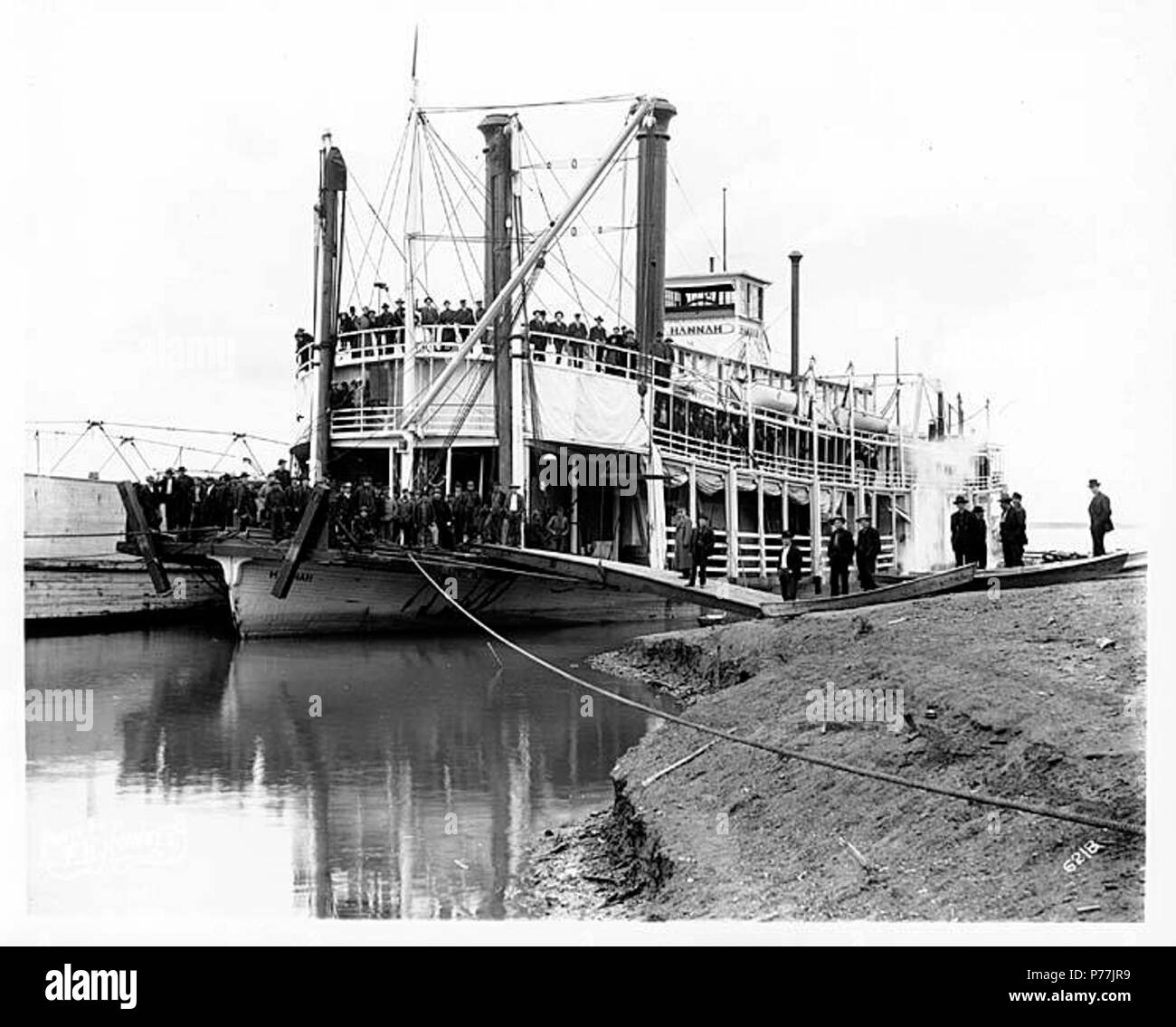 . Inglese: ruota di poppa vaporizzatore HANNAH legata a riverbank, ca. 1904 . Inglese: didascalia sulla immagine: 6218 sul verso dell'immagine: sistema di cottura a vapore Hannah HANNAH fu costruito nel 1898 dal cantiere navale di Howard a Jeffersonville, Indiana, utilizzando stampi dal fiume Ohio barche BLUFF CITY E DOLPHIN n. 2 e n. 3. Insieme con la sorella di navi di Susie e Sarah, è stata spedita in sezioni per Unalaska, dove ella è stata assemblata dall'Alaska Commercial Co. e procedeva da lì a San Michele e la Yukon sotto il suo proprio potere. Essi erano spettacolari barche nella grande tradizione del Western river pacchetti, in particolare alla vicina Foto Stock