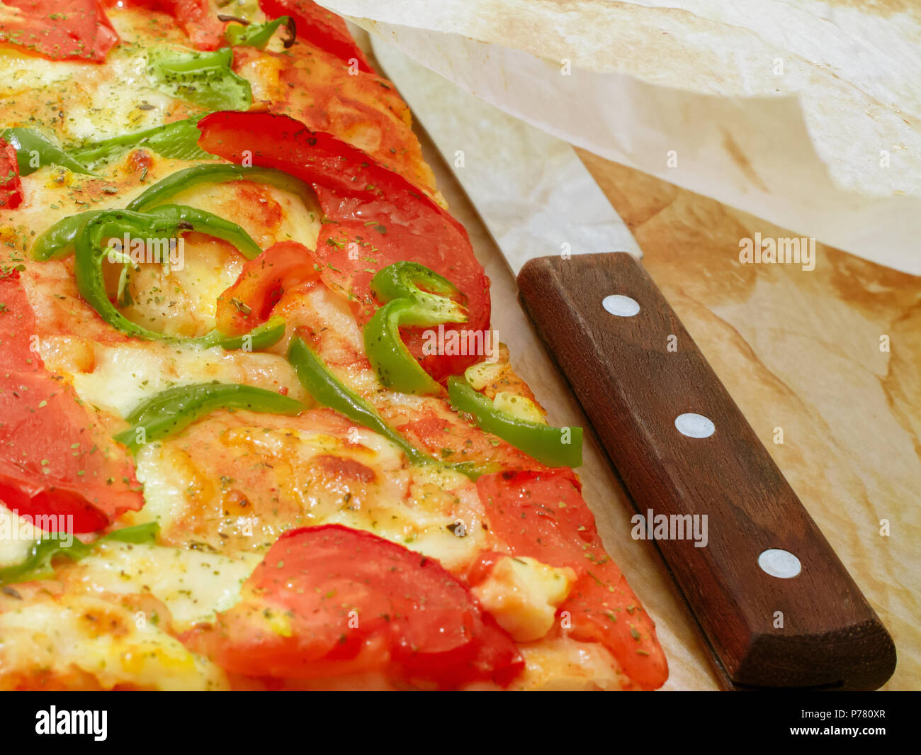 Freschi di forno pezzi di pizza e il coltello sotto la carta pergamena. Foto Stock