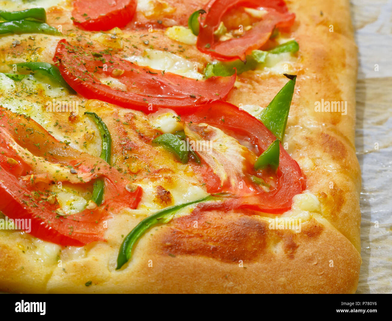 Freschi di forno pezzi di pizza con pomodori rossi, peperone verde e cheeze sulla carta pergamena. Foto Stock