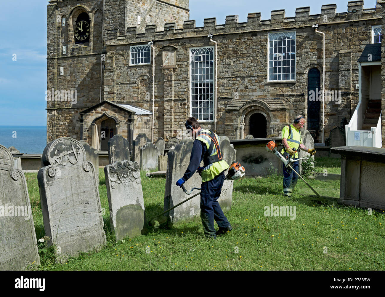 Gli uomini il taglio di erba, Chiesa di Santa Maria, Whitby, North Yorkshire, Inghilterra, Regno Unito Foto Stock