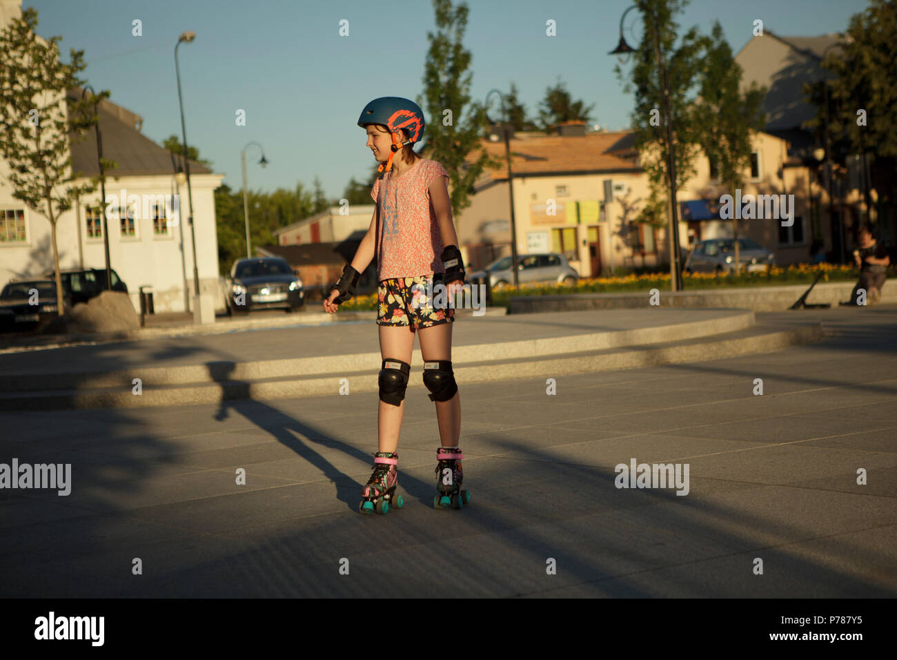 Girll ridinig su rollerskates sulla piazza della città, estate, sera Foto Stock