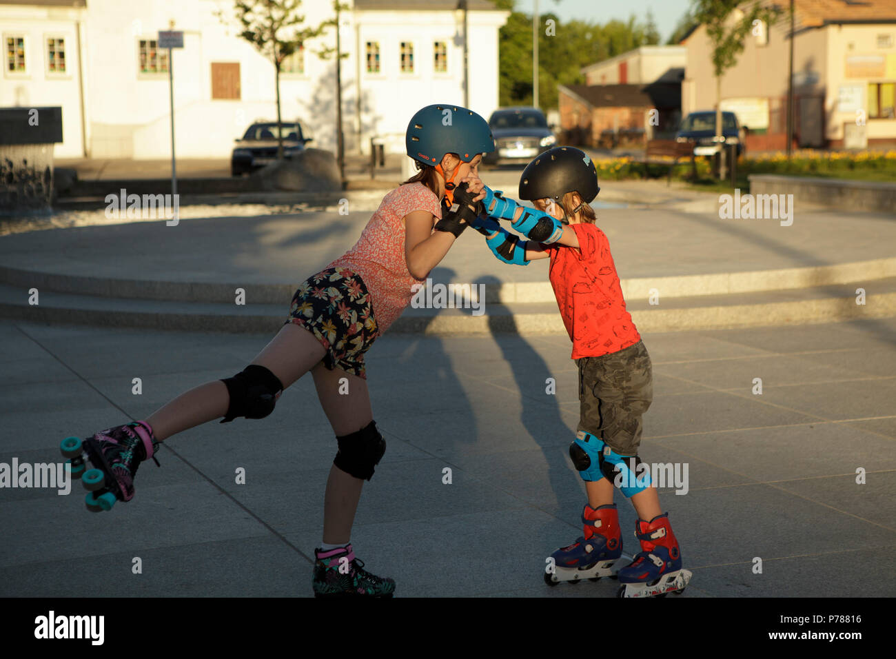 Due bambini che giocano/ballo su pattini a rotelle sulla piazza della città Foto Stock