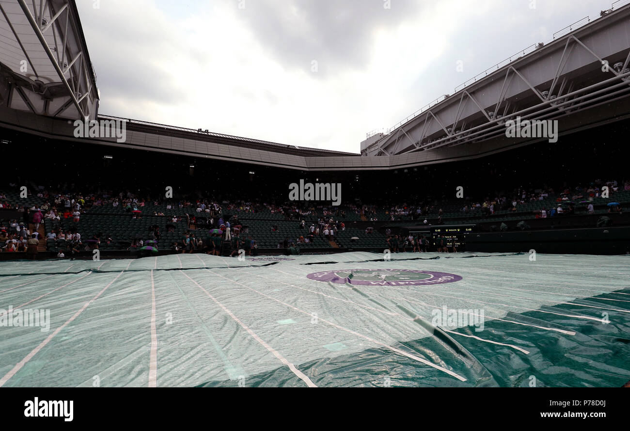 Il personale di terra mettere le copertine sul Centre Court come la pioggia smette di giocare il giorno tre i campionati di Wimbledon al All England Lawn Tennis e Croquet Club, Wimbledon. Foto Stock