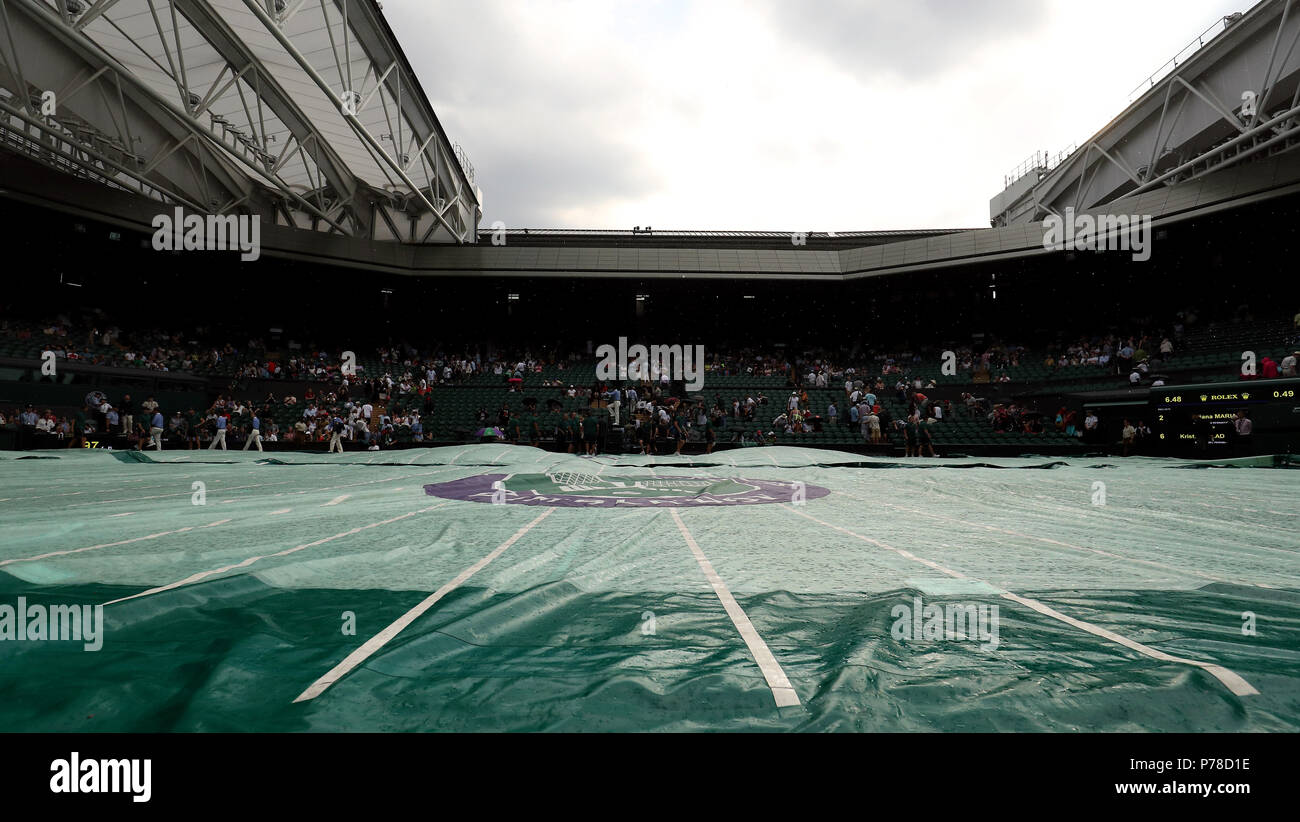 Il personale di terra mettere le copertine sul Centre Court come la pioggia smette di giocare il giorno tre i campionati di Wimbledon al All England Lawn Tennis e Croquet Club, Wimbledon. Foto Stock