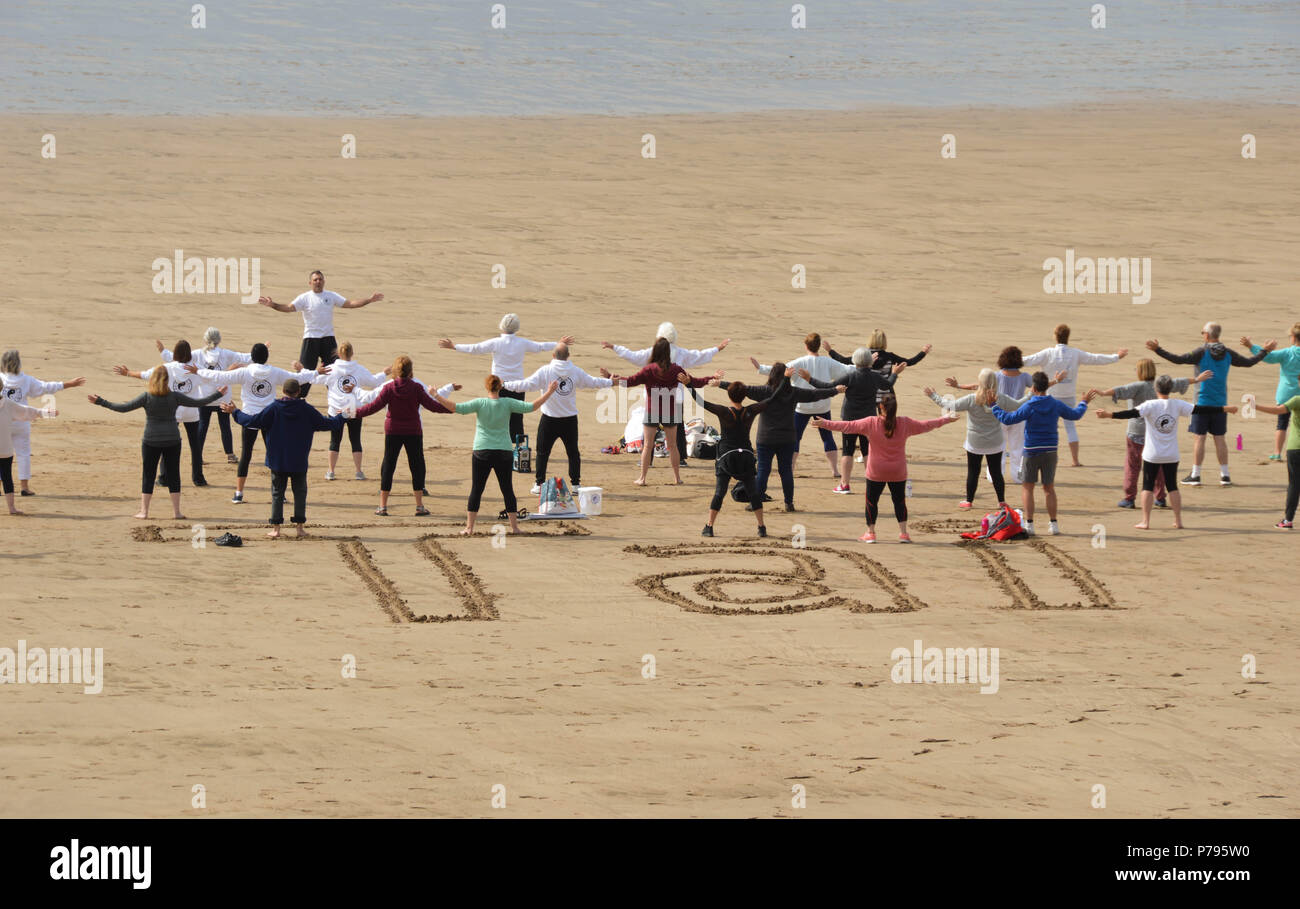 Un gruppo di persone con istruttore in Tai Chi lezione sulla spiaggia di Barry Island, Galles del Sud Foto Stock