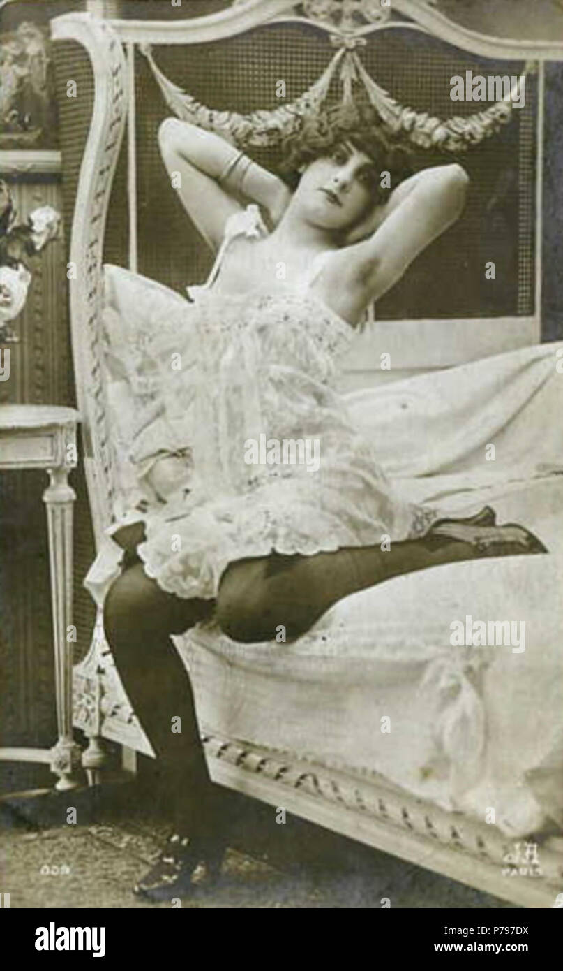 Inglese: donna seduta sul letto, mani dietro la testa, gomiti sollevati; indossare indumenti intimi, calze e scarpe con i tacchi alti . tra il 1910 e il 1917 6 Agelou13 Foto Stock