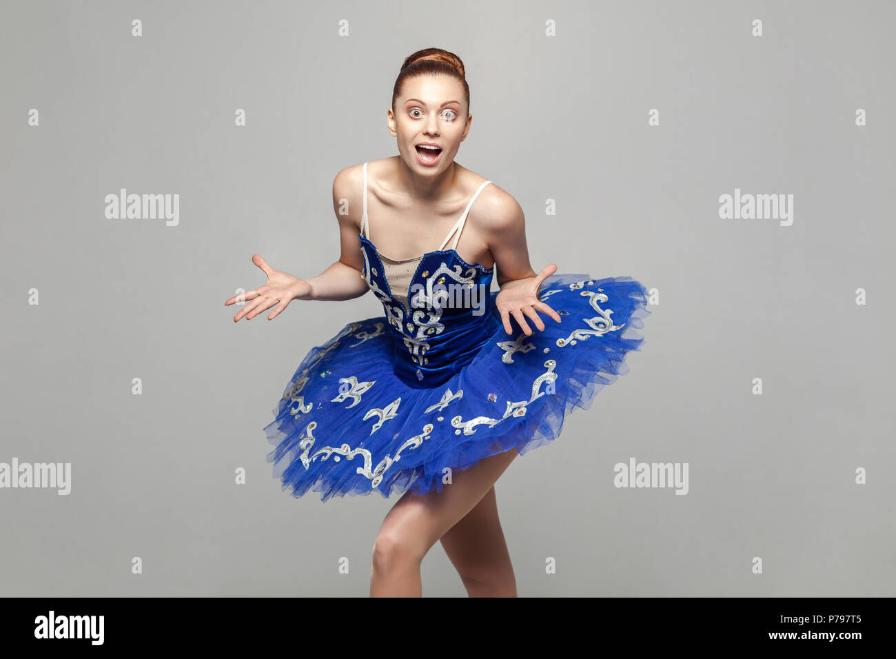 Wow, la sua incredibile. ballerina donna in costume blu con il trucco e bun  raccolti capelli stile in piedi contro lo sfondo grigio guardando la  fotocamera. em Foto stock - Alamy