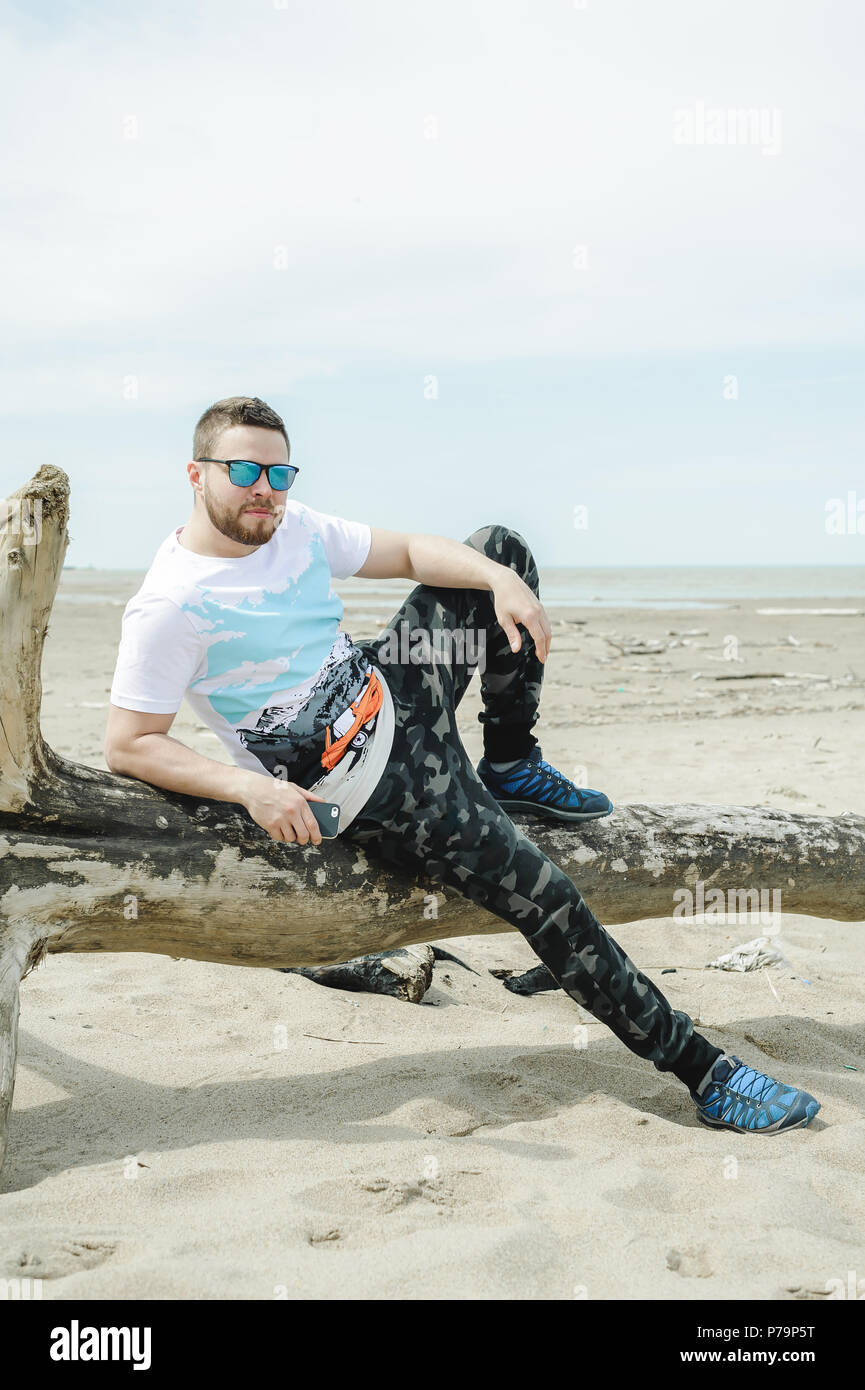 Giovane uomo barbuto, vestito in abiti giovanili, viaggia per mare, le avventure in una calda giornata estiva. Foto Stock
