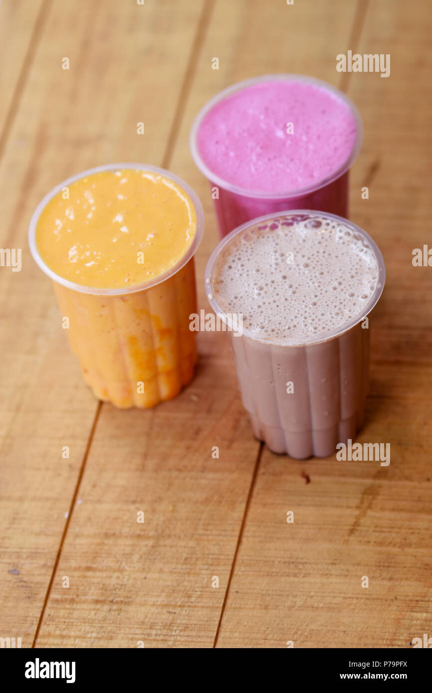 Tre bicchieri di vari milkshakes.Strawberry, cioccolato e vaniglia milkshake su sfondo di legno Foto Stock