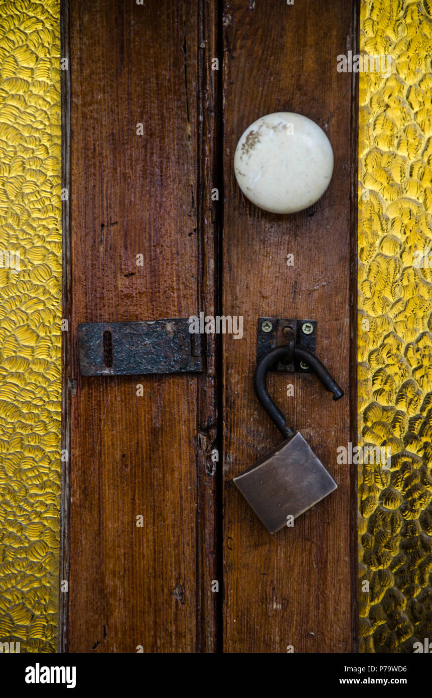 Bloccare con un lucchetto aperto di una vecchia porta di legno con vetro Foto Stock
