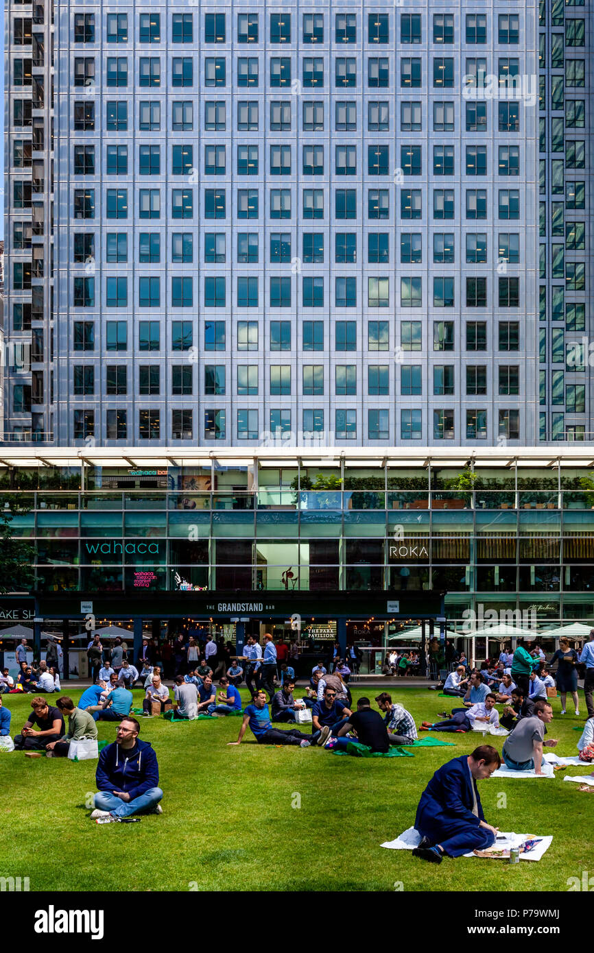 Gli impiegati seduti sul prato del pranzo, Canary Wharf, London, Regno Unito Foto Stock