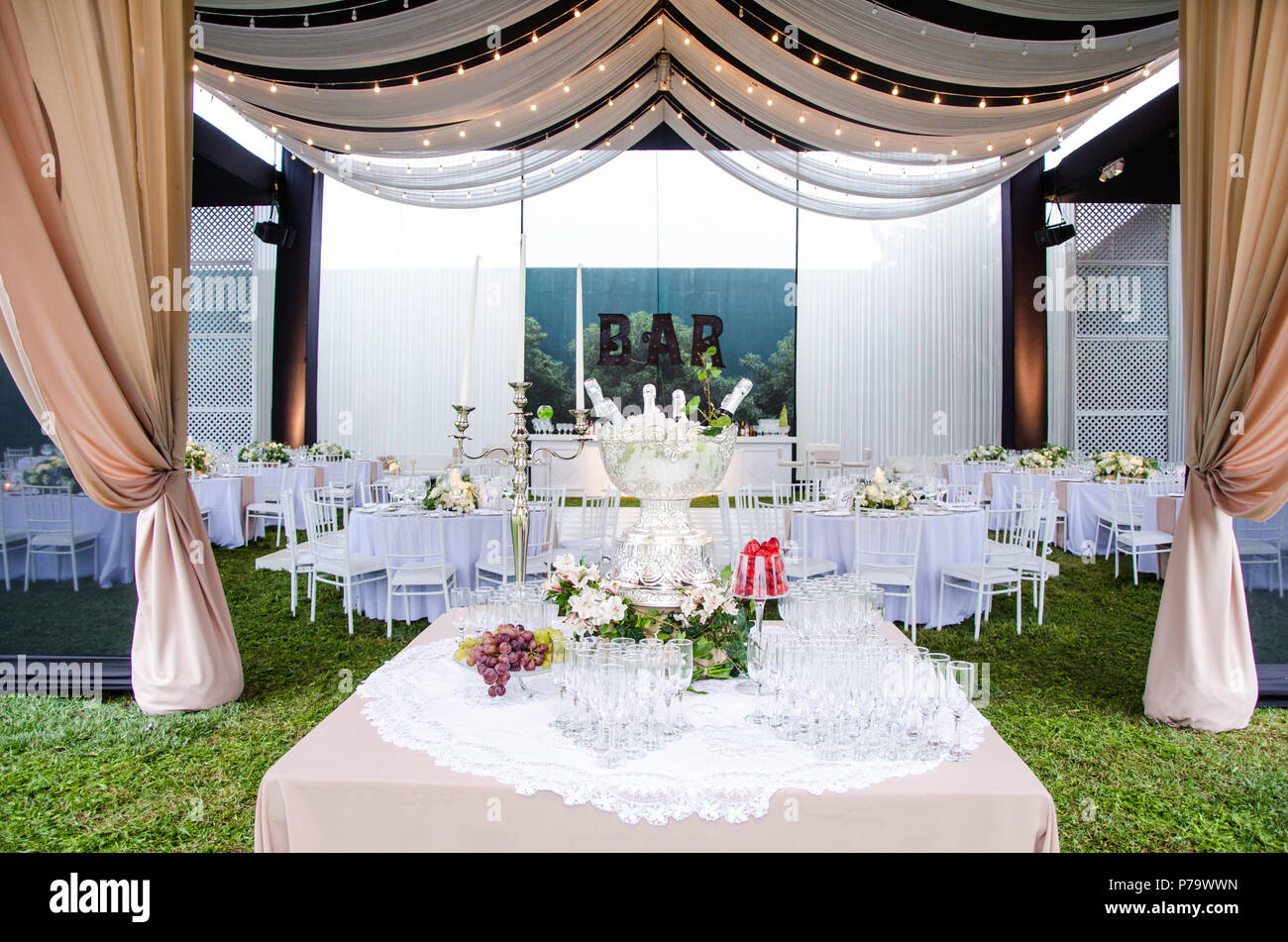 Un ampio angolo di visione di un ricevimento di matrimonio venue, con pista da ballo e tabelle circostante. Un grande lampadario nel mezzo della camera dispone di attrezzatura drappeggiati con mini luci. Foto Stock