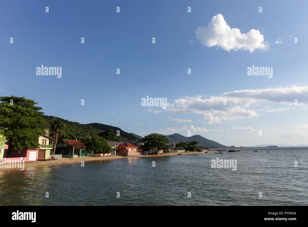 Florianopolis, stato di Santa Catarina, Brasile. Bellissima spiaggia paesaggio in un villaggio di pescatori con alberi, case colorate e cielo blu d'estate. Foto Stock