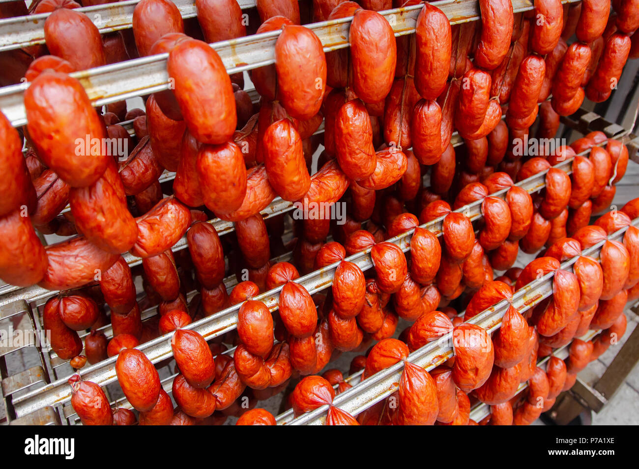 La salsiccia. Salsiccia della linea di produzione. Salsicce sul contatore per la smokehouse. Produzione industriale di salumi. Foto Stock