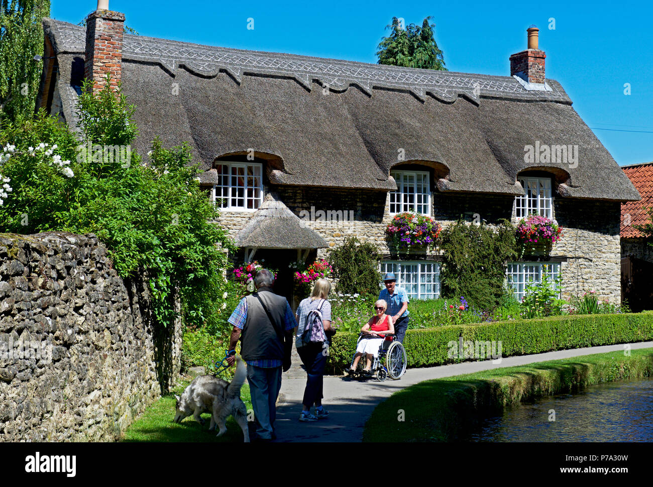 Cottage con il tetto di paglia & Thornton Beck, Thornton-le-Dale, North Yorkshire, Inghilterra, Regno Unito Foto Stock