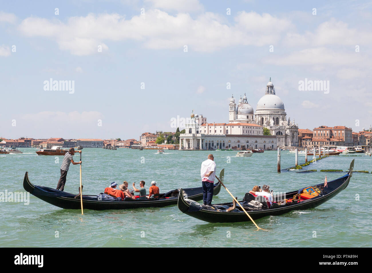 Due gondolieri turisti a remi in gondole St Marks Basin, Venezia, Veneto, Italia con Punta della Dogana e la Basilica di Santa Maria della Salute Foto Stock