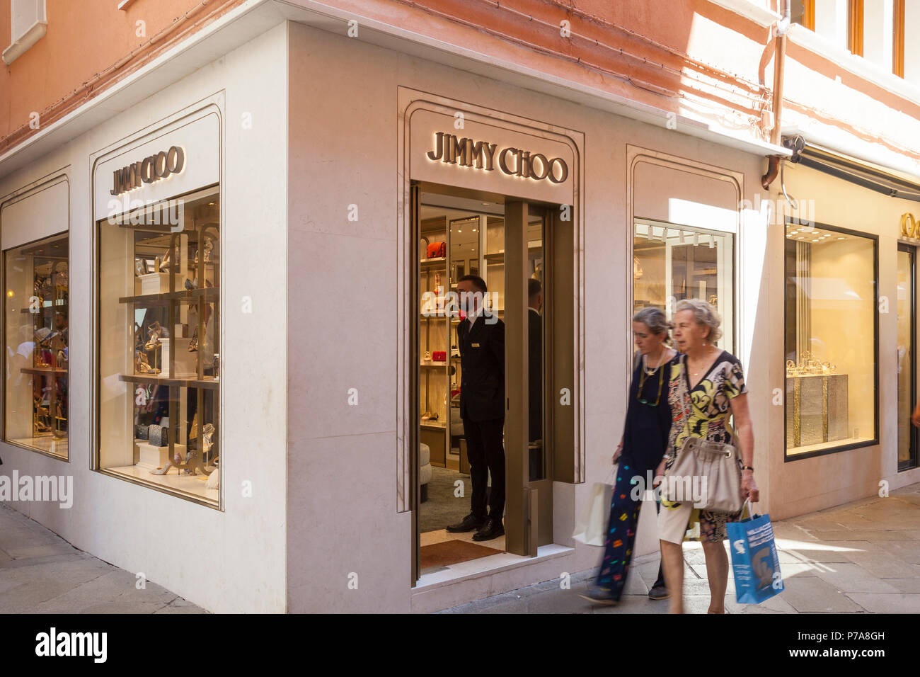 Il Jimmy Choo Store, Piazza San Marco, Venezia, Veneto, Italia vendita di scarpe da donna e accessori. Due donne sfocate passando dalla facciata esterna Foto Stock