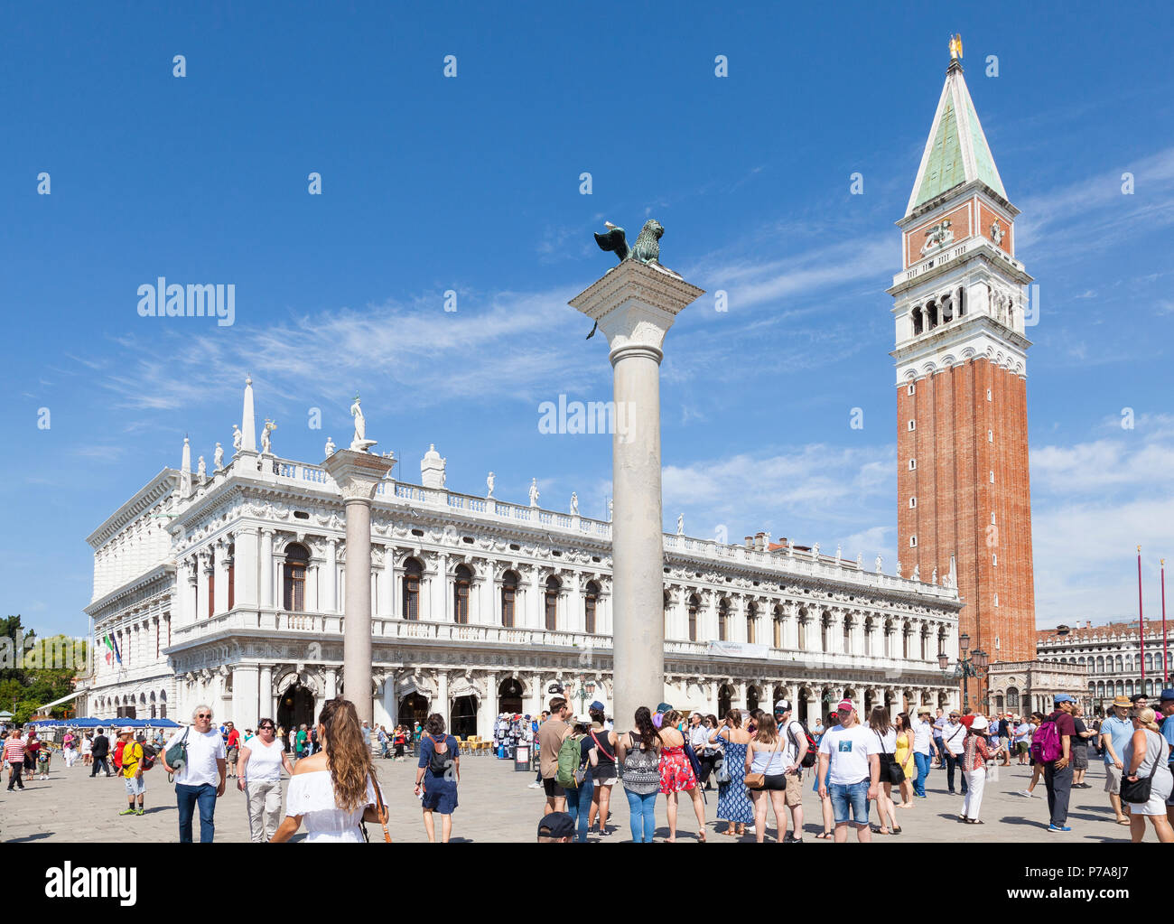 Folla turistica nella parte anteriore della Biblioteca Marciana in Piazetta San Marco, Venezia, Veneto, Itlay con la Torre Campanaria (campanile) e due colonne Foto Stock
