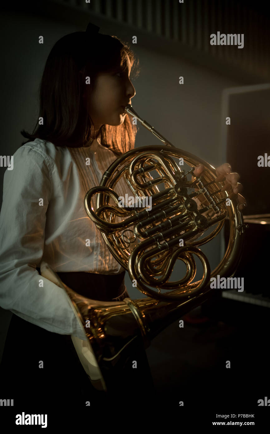 Schoolgirl giocare corno francese nella scuola di musica Foto Stock