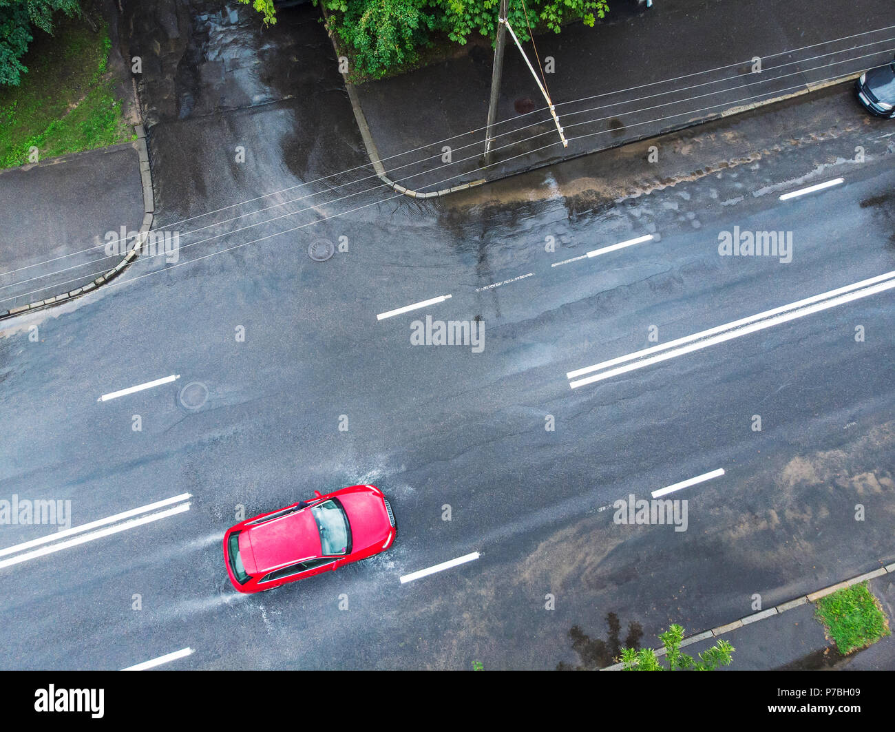 Auto rossa attraversando una strada allagata dopo heavy rain. vista aerea Foto Stock