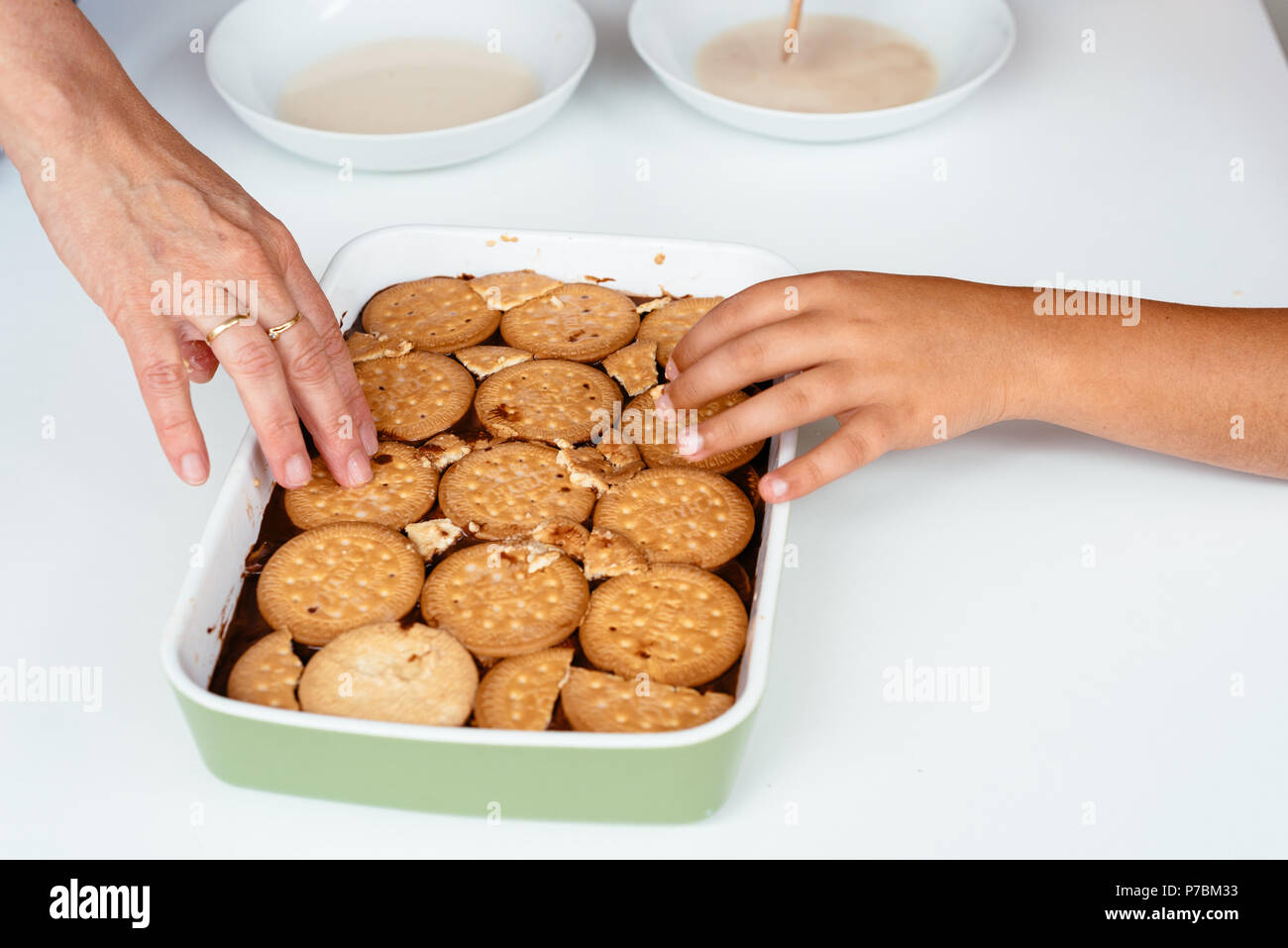 La famiglia la preparazione di cioccolato artigianale torta fatta con biscotti Foto Stock
