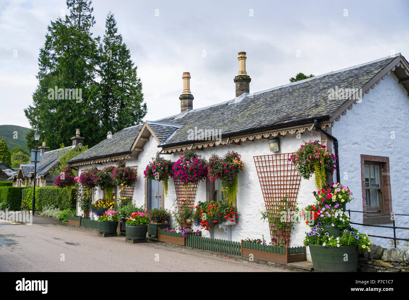 Grazioso cottage con cestelli appesi in Luss sul Loch Lomond. Luss è stato nominato come il più bel villaggio della Scozia. Foto Stock