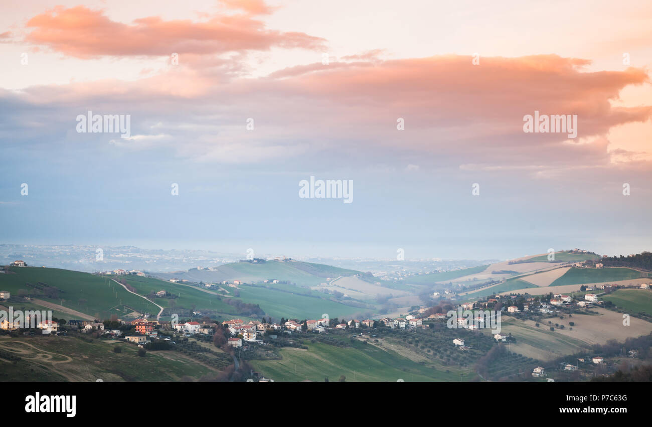 Campagna Italiana, paesaggio rurale. Provincia di Fermo, Italia. Paesini arroccati sulle colline colorate sotto il cielo mattutino Foto Stock