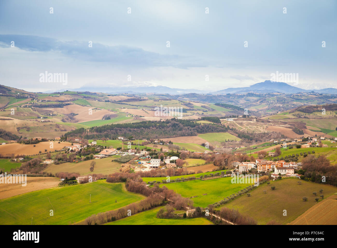 Panorama rurale della campagna italiana in primavera. Provincia di Fermo, Italia. I villaggi e i campi sulle colline sotto blu cielo nuvoloso Foto Stock