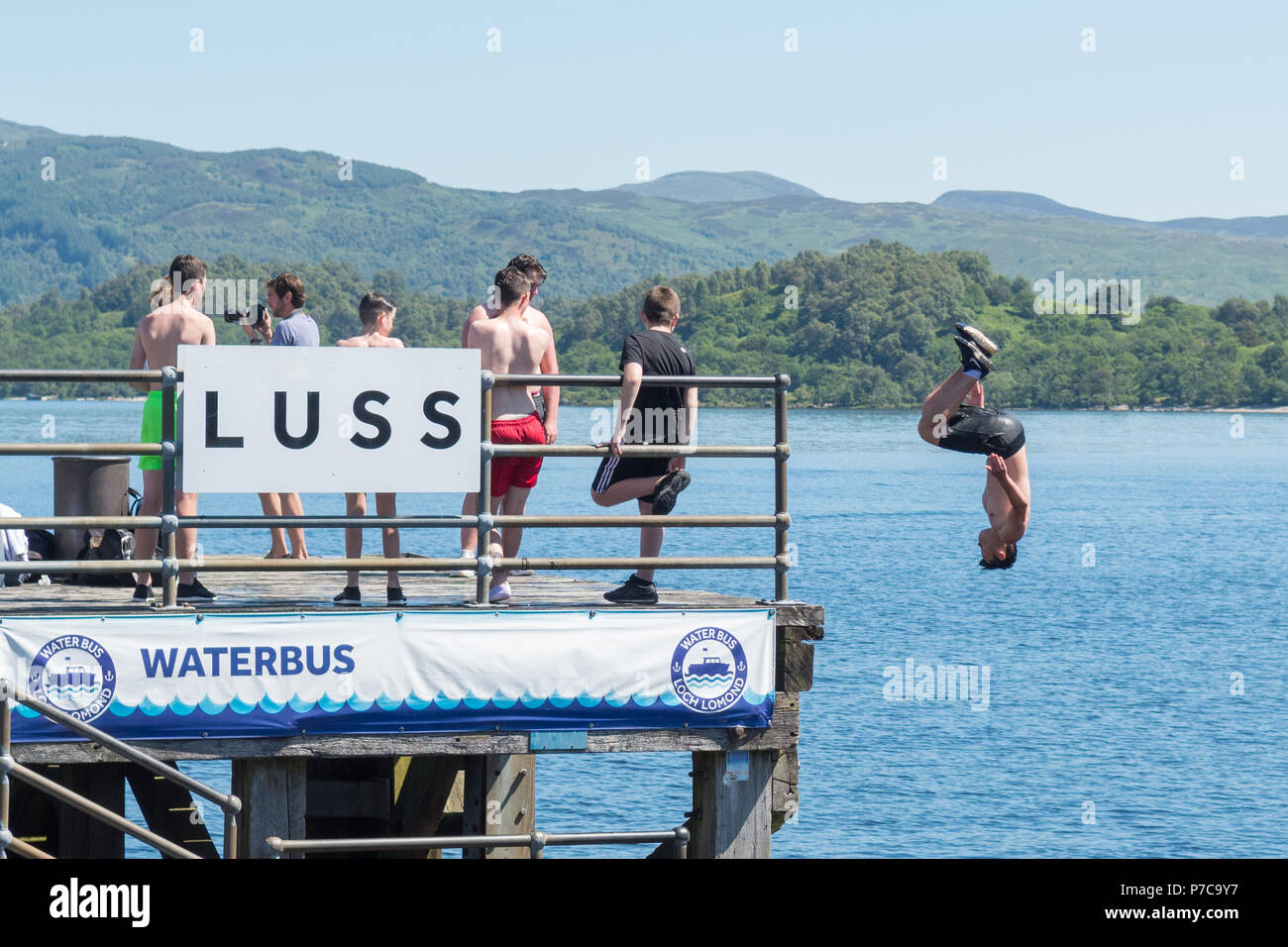 Immersioni subacquee e somersaulting off Luss Pier in Loch Lomond durante la stagione calda, Scotland, Regno Unito Foto Stock