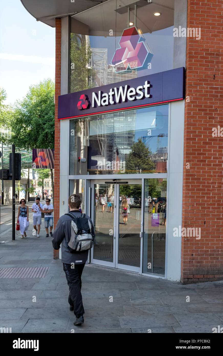 Un giovane uomo passa il al di fuori di una moderna branca della NatWest Bank in Manchester, Regno Unito Foto Stock