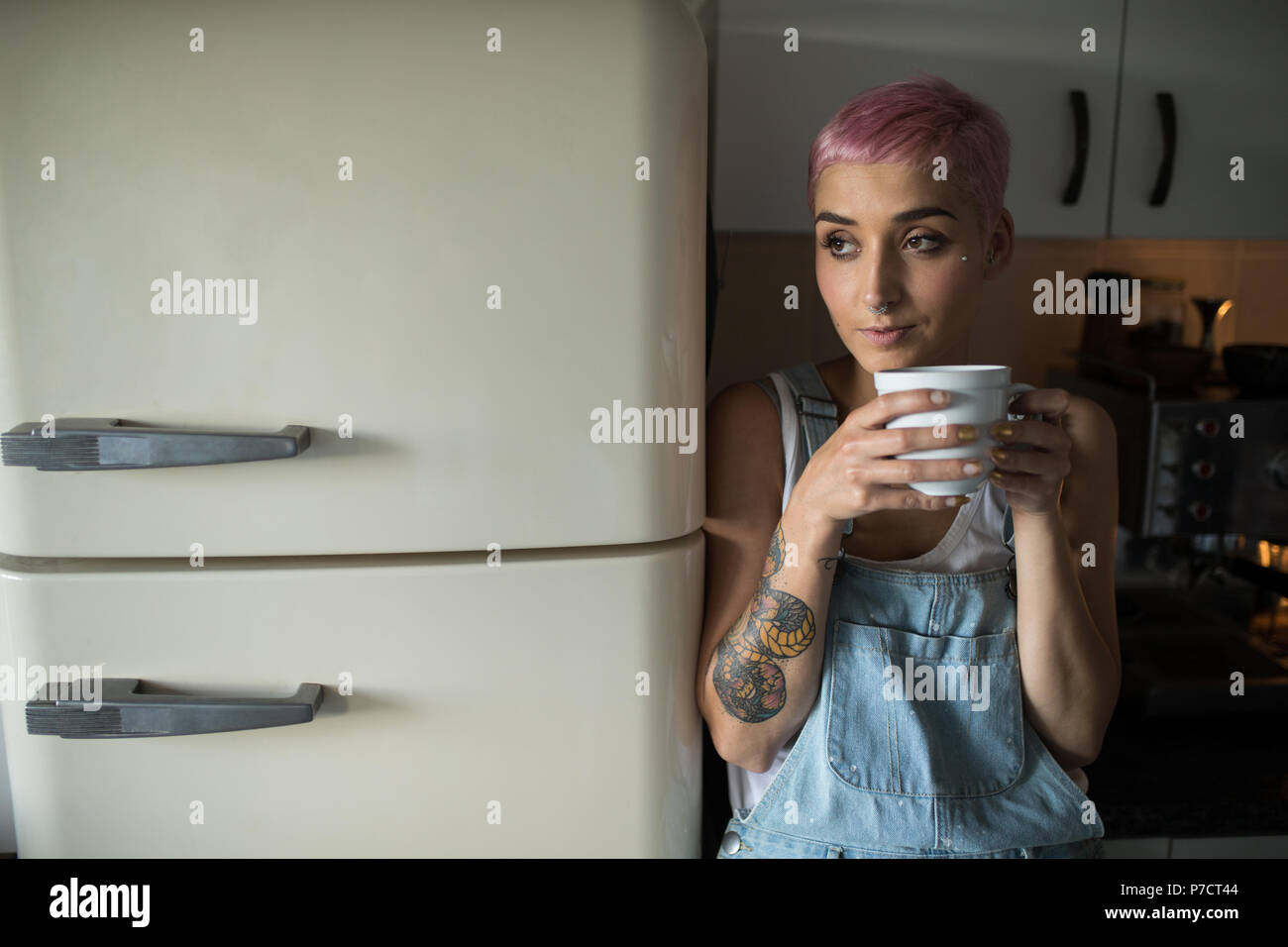 Donna con caffè in cucina a casa Foto Stock