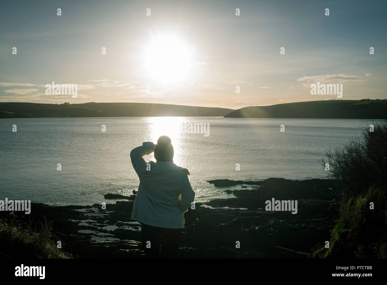 Donna in piedi vicino al fiume lato durante il tramonto Foto Stock