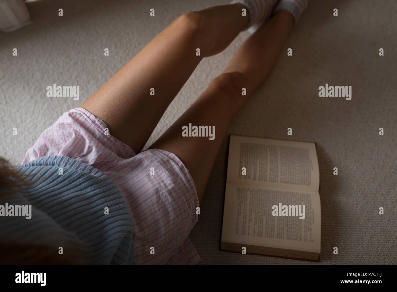 Donna seduta con un libro a casa Foto Stock