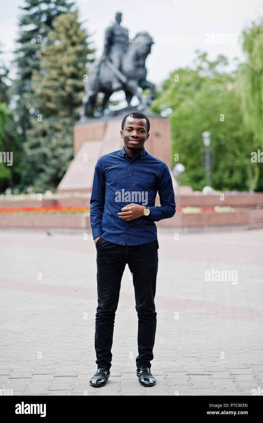 L'uomo africano poste lungo la strada della città di usura sulla maglietta  blu e pantaloni neri Foto stock - Alamy