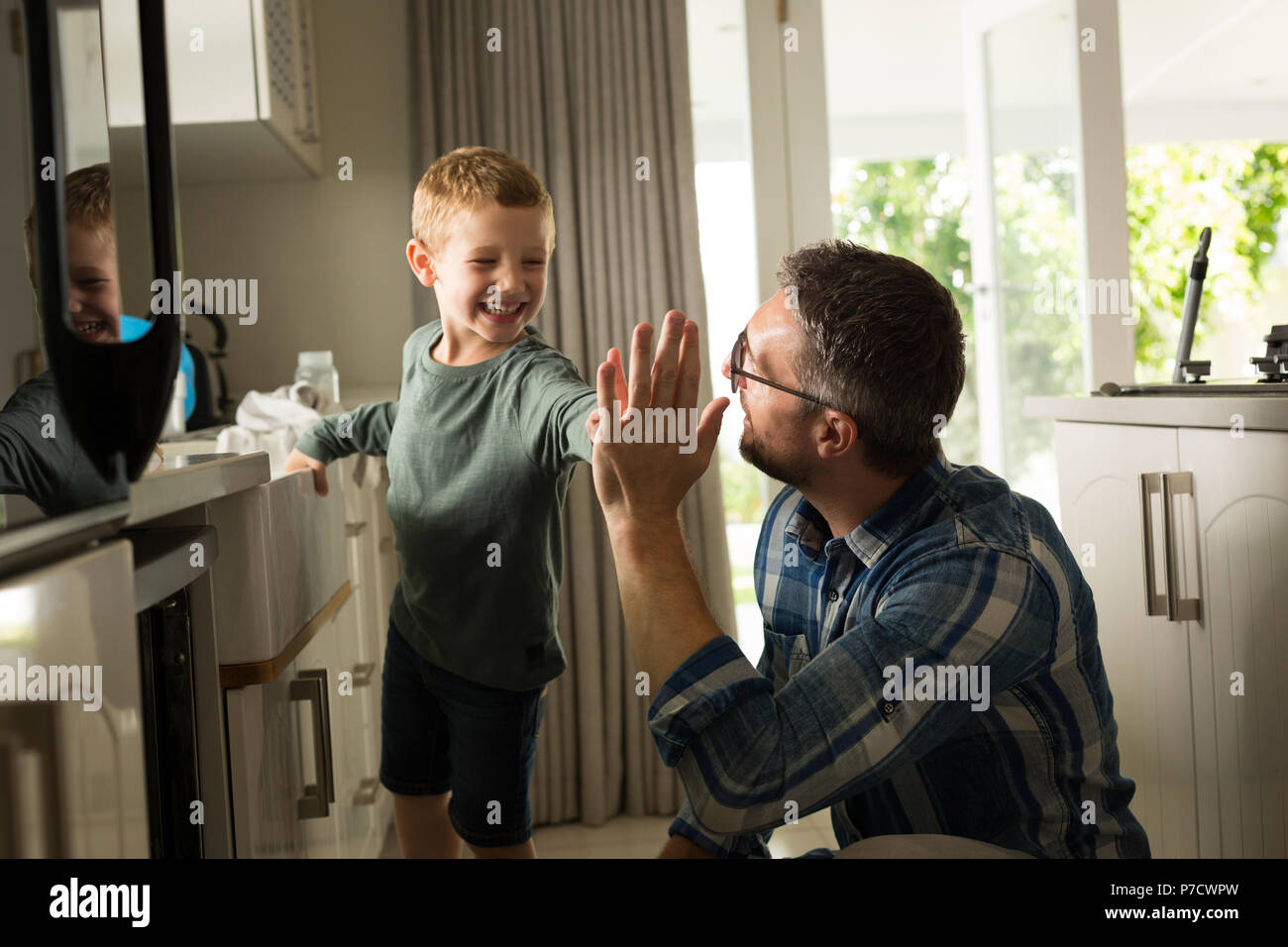 Padre e figlio dando alta cinque per ogni altro in cucina Foto Stock