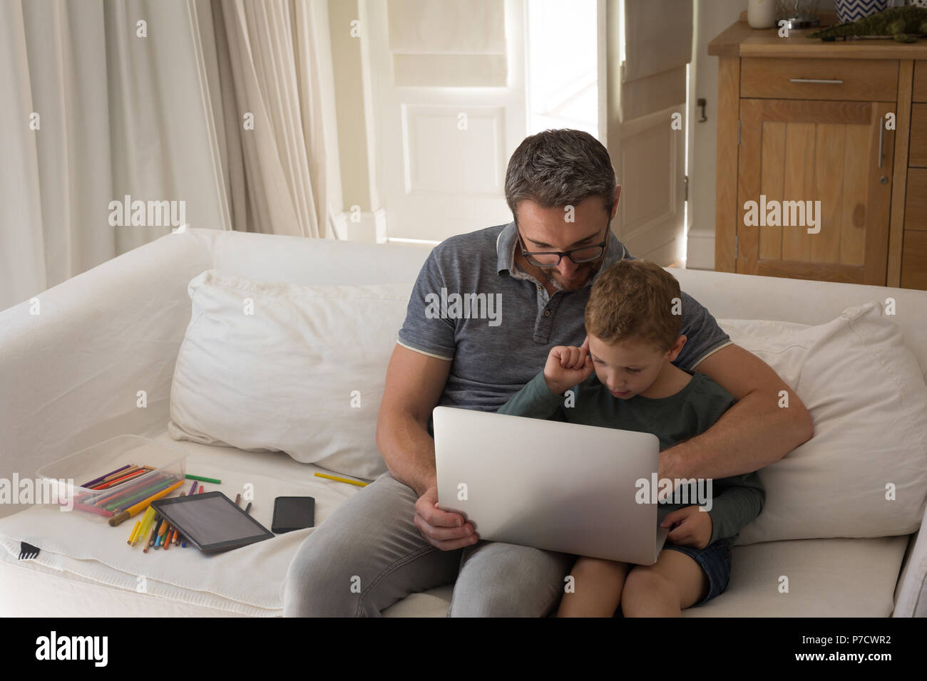 Padre e figlio utilizzando laptop in salotto Foto Stock