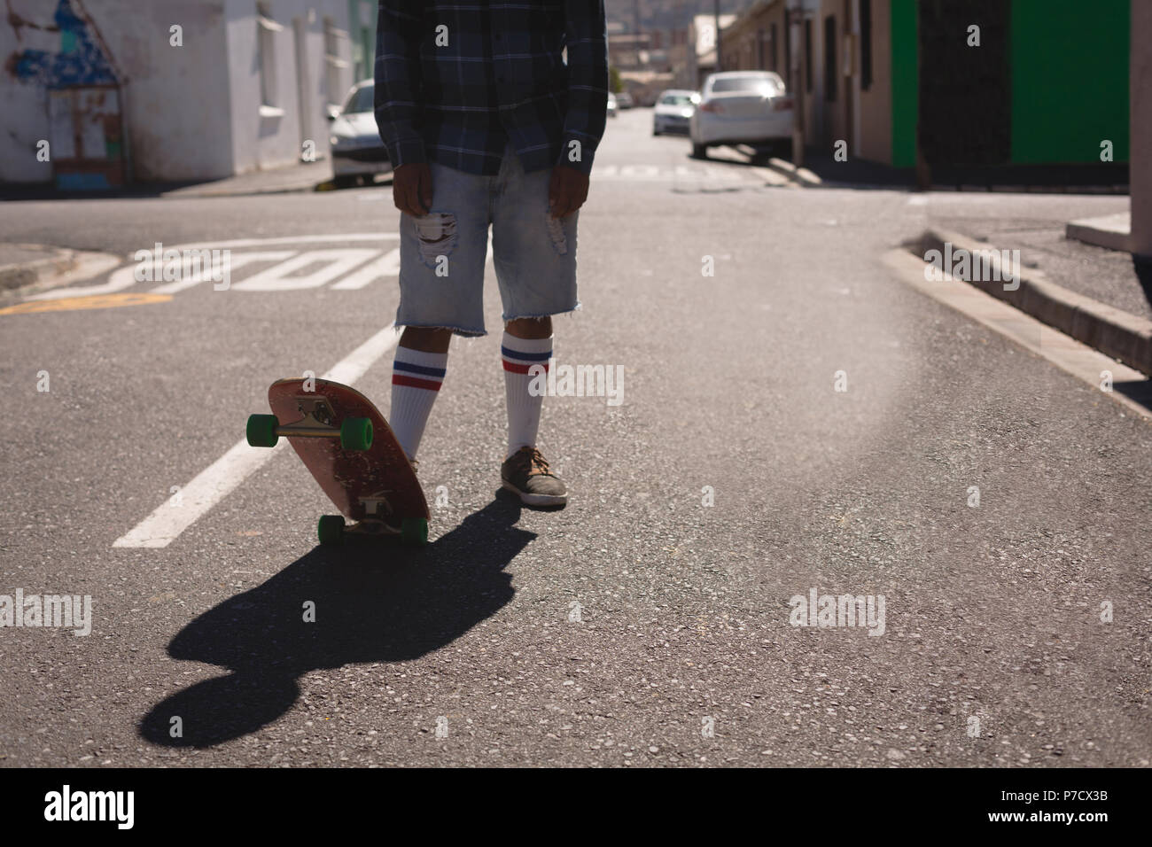 Uomo in piedi con lo skateboard in strada Foto Stock