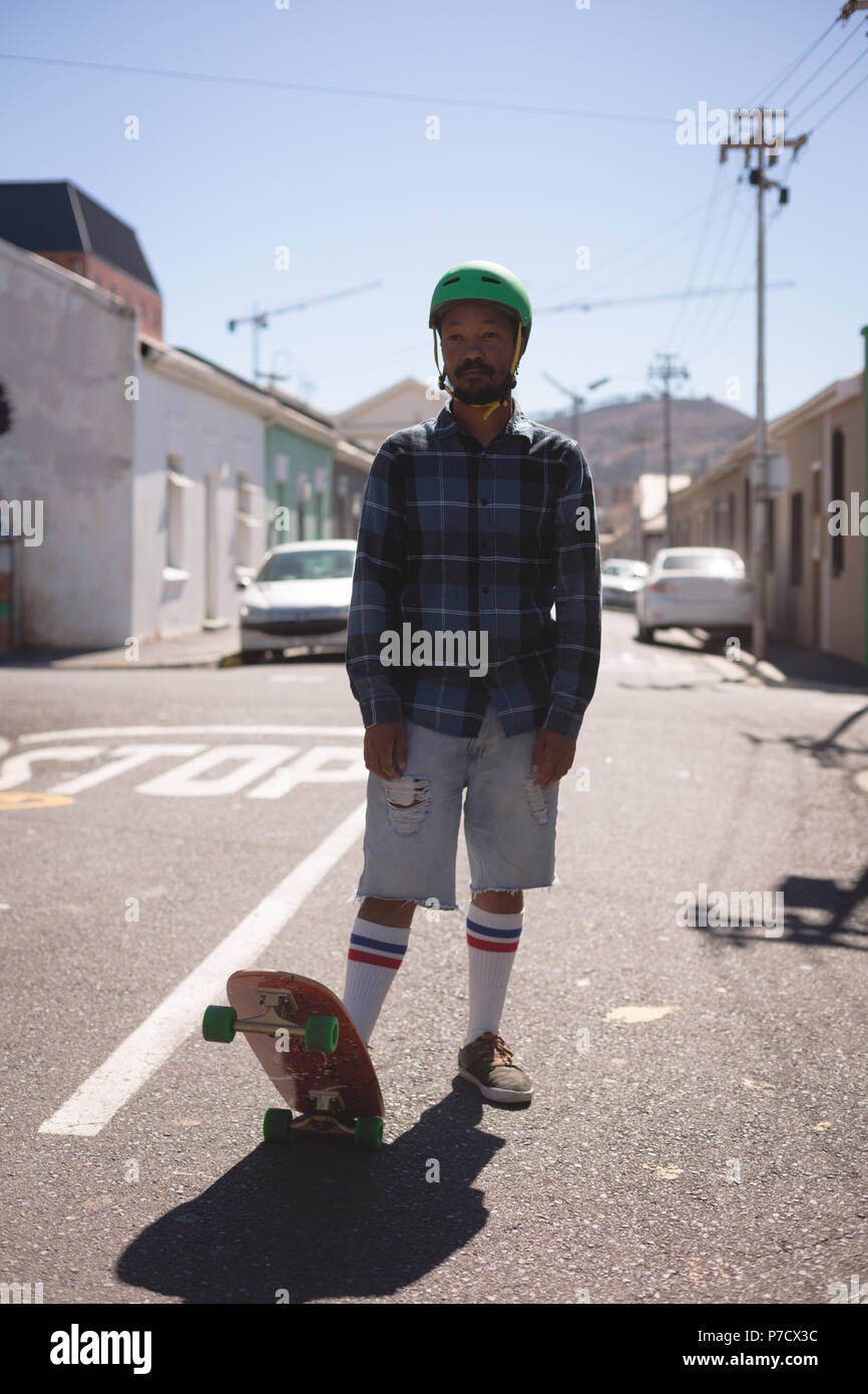 Uomo in piedi con lo skateboard in strada Foto Stock