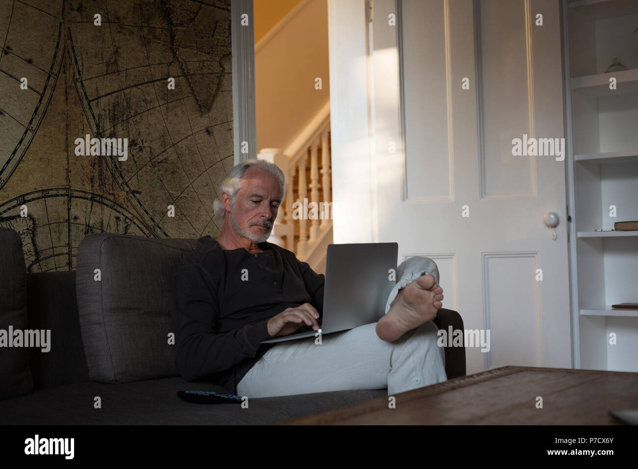 Senior uomo utilizzando laptop in salotto Foto Stock