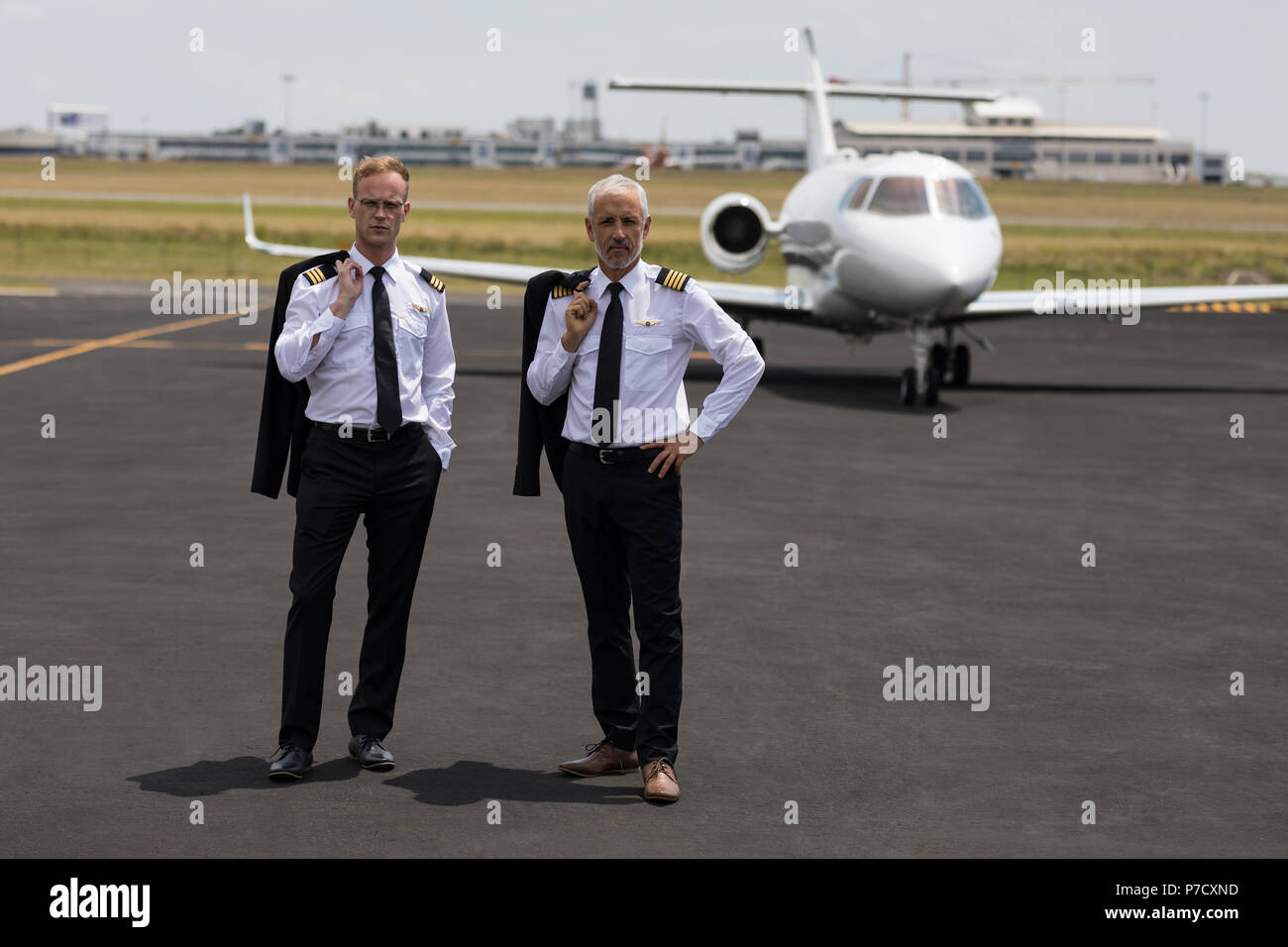 Due piloti di sesso maschile in piedi su un runaway Foto Stock