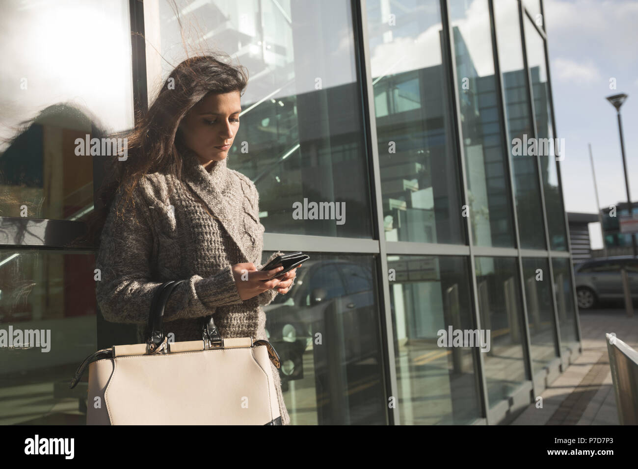 Donna che utilizza il telefono cellulare al di fuori di una struttura edile Foto Stock