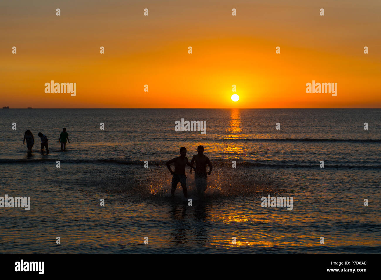 Silhouette, nuotatori al tramonto a Rio de la Plata, la spiaggia della città di Montevideo, Uruguay Foto Stock