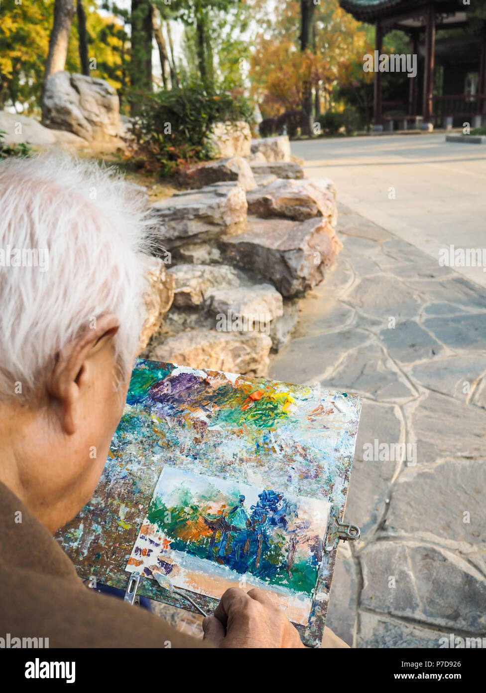 Ritirato uomo asiatico usando un coltello di pittura per dipingere un tempio tradizionale Cinese in Xuanwu lake park, Nanjing, Cina Foto Stock Ritirato uomo asiatico usando un coltello di pittura per dipingere un tempio tradizionale Cinese in Xuanwu lake park, Nanjing, Cina Foto Stock